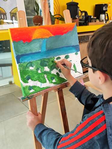 Un niño pintando un paisaje en el caballete
