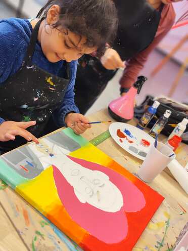 Dos niños pintando juntos sobre un lienzo grande