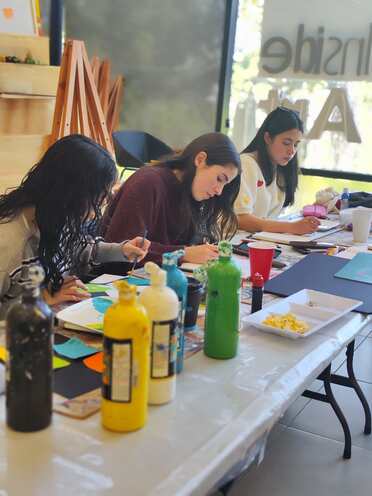 La mesa larga llena de témperas y trabajos en proceso
