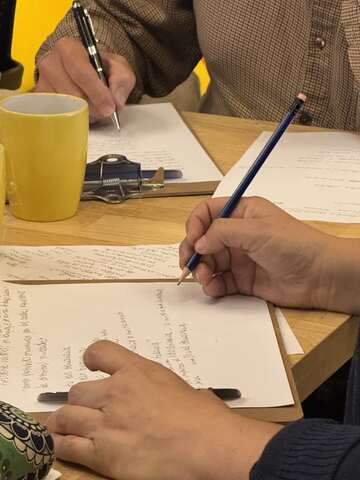Manos escribiendo en un cuaderno durante un encuentro de PALABRIA